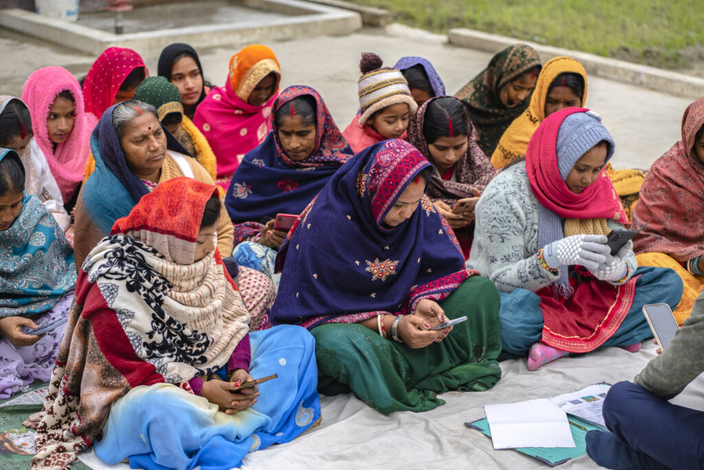 A group of women in India using their phones during a digital and financial capability training.