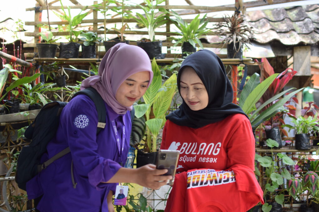 Amartha staff shows how to use their digital platform to a female user in Indonesia