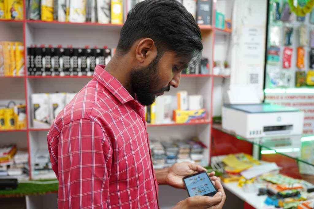 A man looking at a training video on his mobile phone in his shop. 