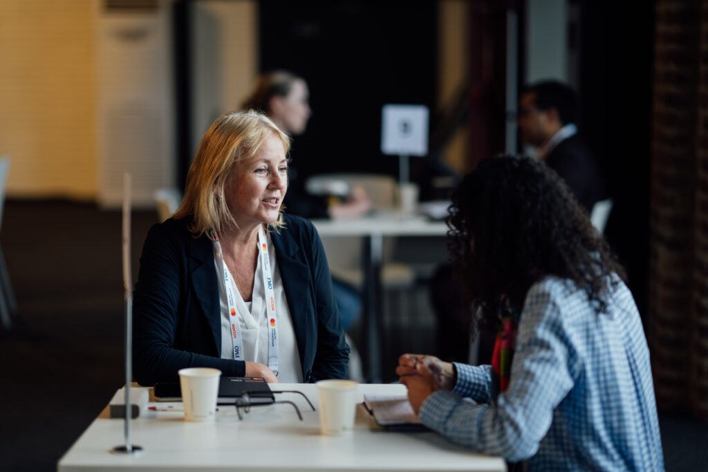 two women sit at a table and chat