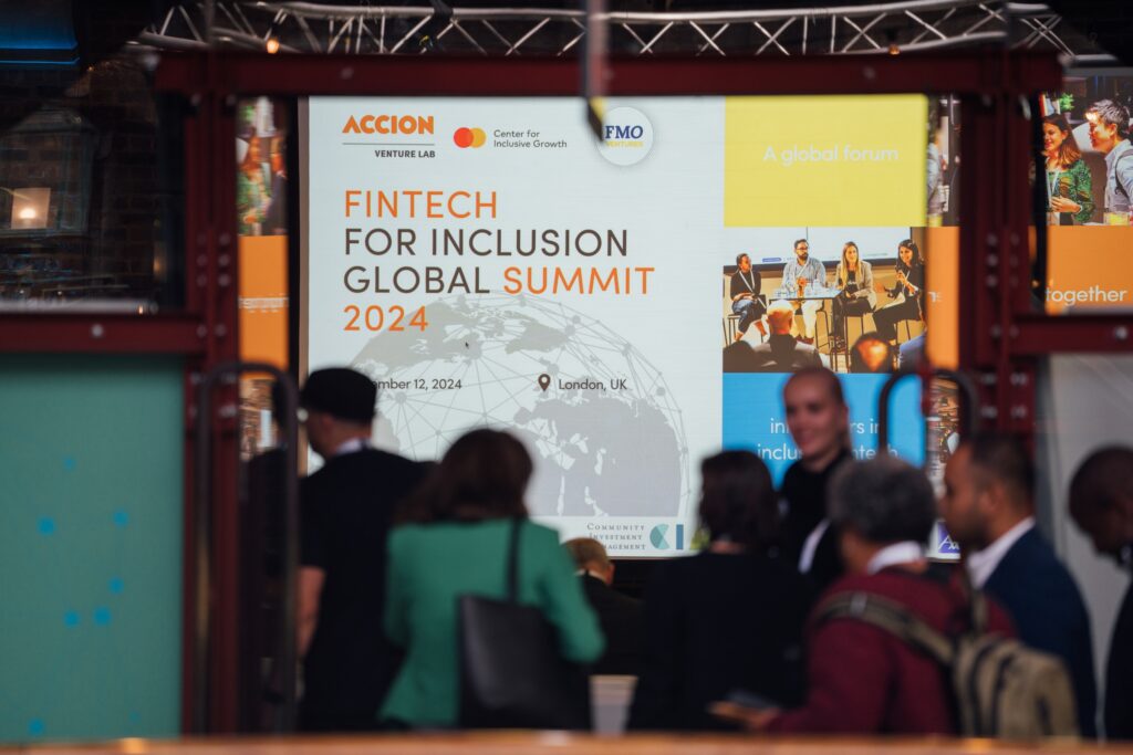 Attendees walk pass by the banner of Fintech for Inclusion Global Summit 2024