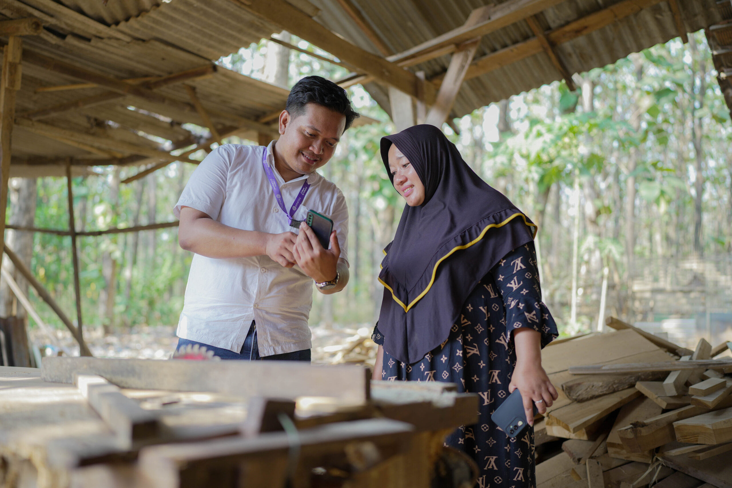 A man training a woman on digital payments via phone. 