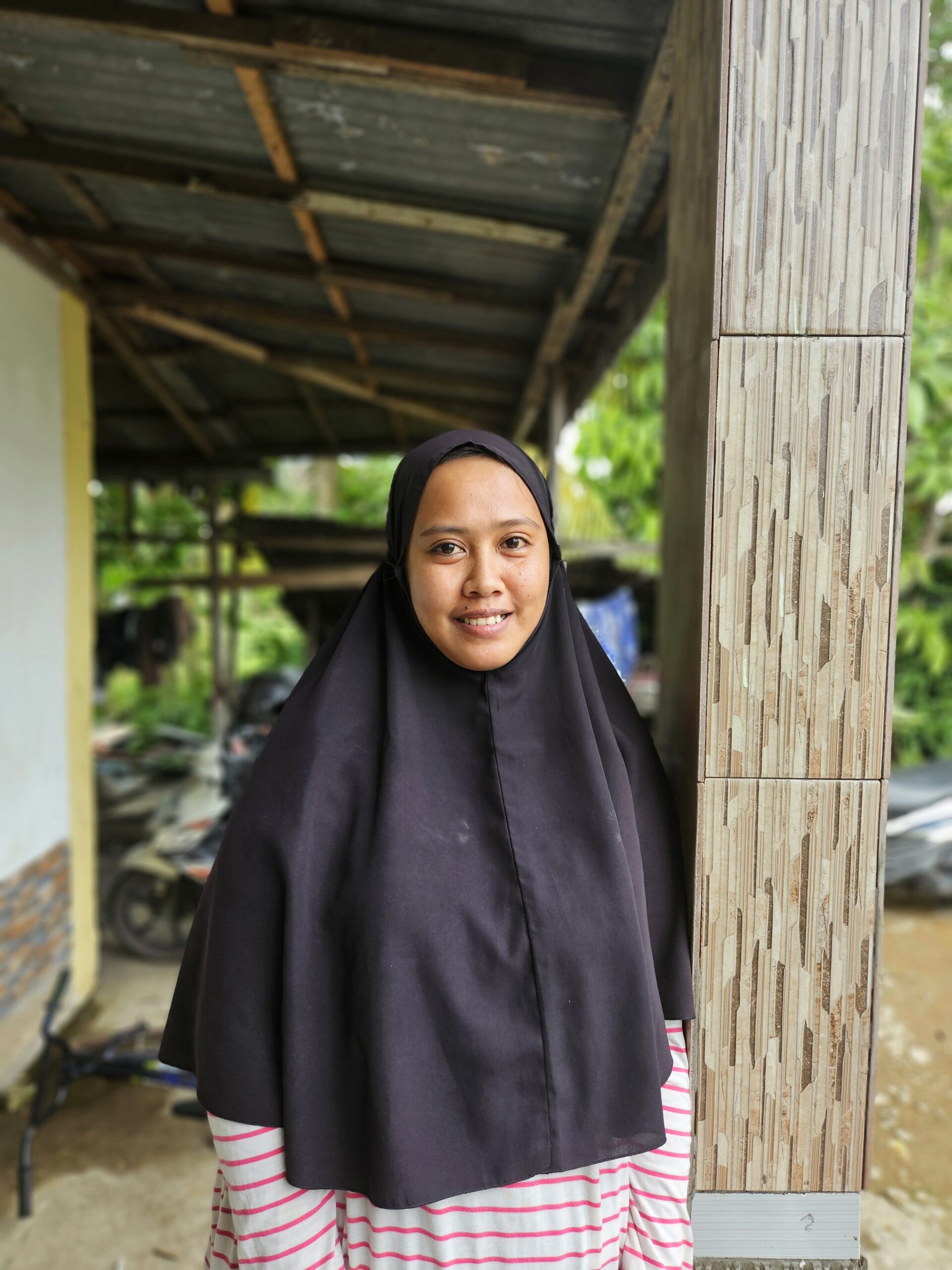 A woman standing outside her house. 