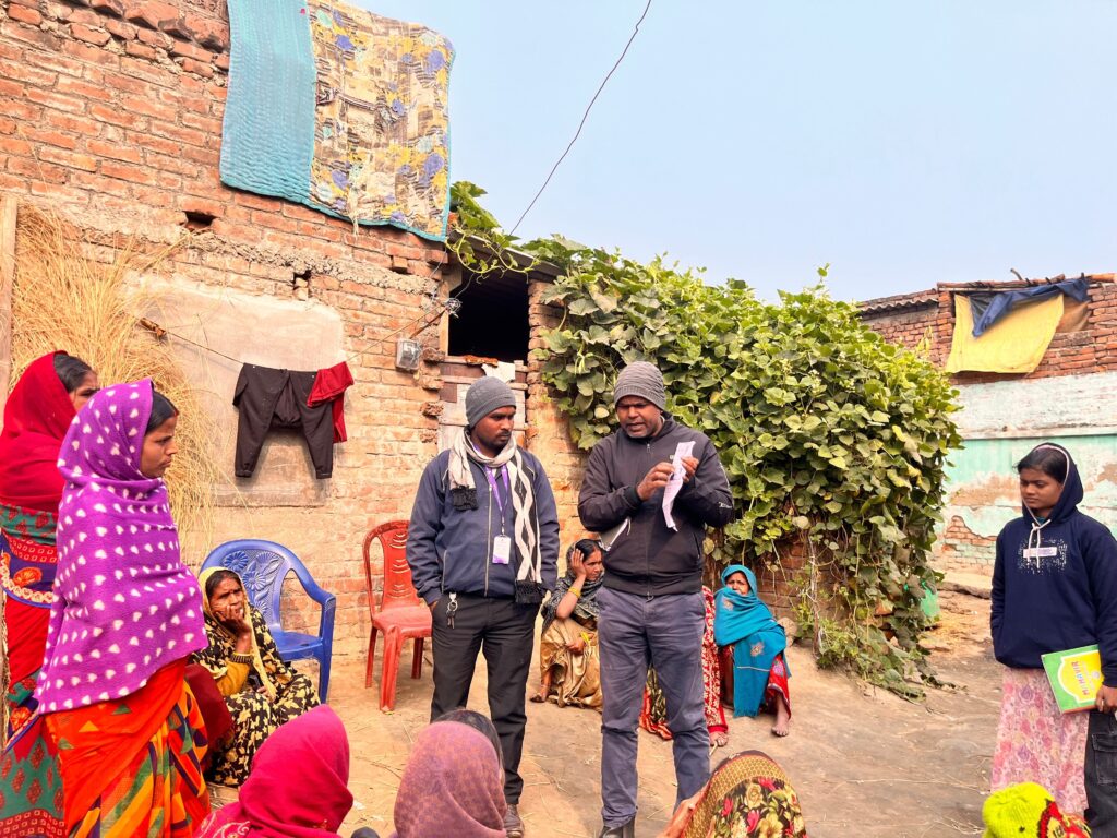 Two men conducting a training with a group of women in a village. 